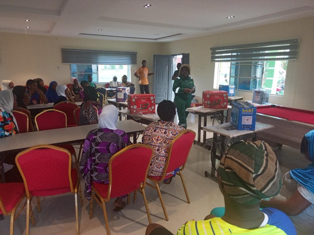 Women and young people seated at the foundation's empowerment programme, with sewing machines set out at the front of the hall